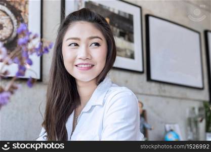 Beautiful young Asian woman smile and looking up and thinking in coffee shop cafe
