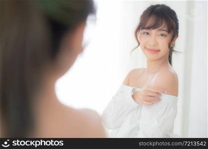 Beautiful young asian woman smiling with clothes trying on dressed up fitting with modern and looking reflect mirror in the room, girl choose clothes fashion with happy and cheerful, lifestyle concept.
