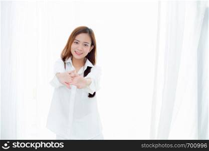 Beautiful young asian woman stretch and relax standing in bed after wake up morning at bedroom, new day and resting for wellness, lifestyle concept.