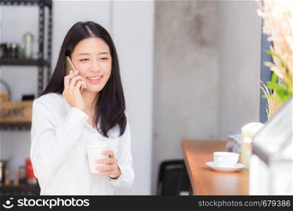 Beautiful young asian woman talking phone and smile in the coffee shop, businesswoman sitting in cafe free time, freelancer female calling telephone, communication concept.