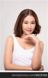 Beautiful Young Asian Woman with short hair Looking While Touching Chin feeling so happy and cheerful with healthy Clean and Fresh skin,isolated on gray background,Beauty Cosmetics Concept