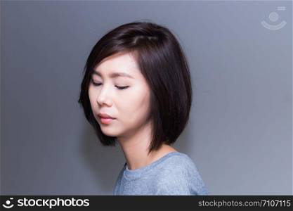 Beautiful young Asian woman with short haircut on studio background.