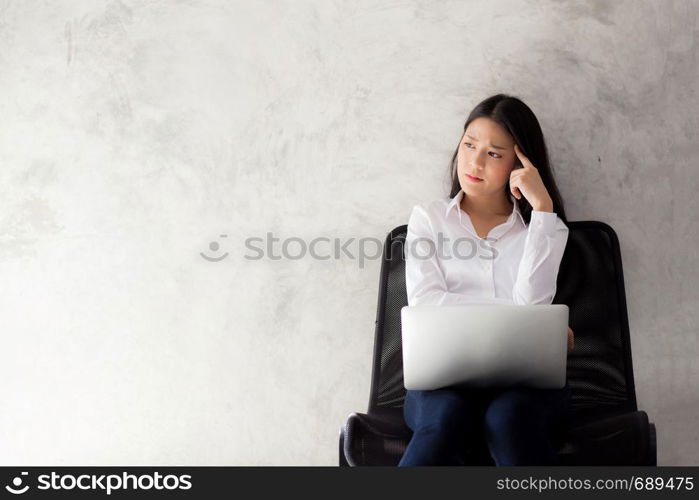 Beautiful young asian woman working and thinking with problem to stress and unhappy, businesswoman with laptop computer on cement background with emotion, freelance business concept.