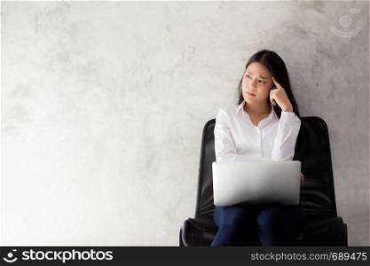 Beautiful young asian woman working and thinking with problem to stress and unhappy, businesswoman with laptop computer on cement background with emotion, freelance business concept.