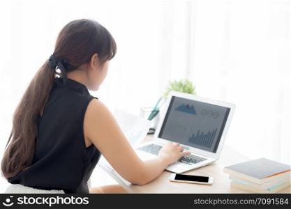 Beautiful young asian woman working and typing with laptop computer at office, businesswoman looking graph diagram analysis statistic data of finance, girl using notebook, profit growth, business concept.
