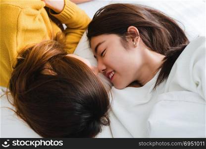 Beautiful young asian women LGBT lesbian happy couple hugging and smiling while lying together in bed under blanket at home. Funny women after wake up. LGBT lesbian couple together indoors concept.
