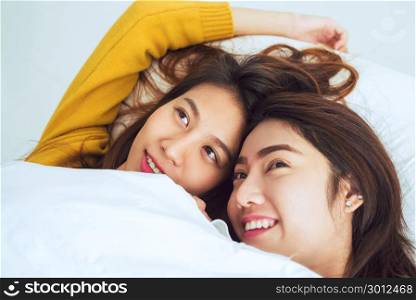 Beautiful young asian women LGBT lesbian happy couple showing surprise and looking at camera while lying in bed under blanket. Funny women after wake up. LGBT Lesbian couple together indoors concept