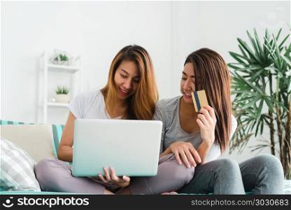 Beautiful young asian women LGBT lesbian happy couple sitting on. Beautiful young asian women LGBT lesbian happy couple sitting on sofa buying online using laptop a computer and credit card in living room at home. LGBT lesbian couple together indoors concept.