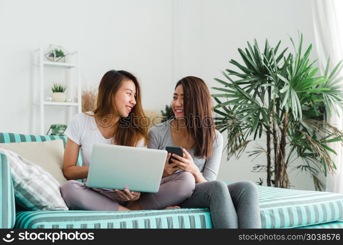 Beautiful young asian women LGBT lesbian happy couple sitting on. Beautiful young asian women LGBT lesbian happy couple sitting on sofa buying online using laptop a computer and phone in living room at home. LGBT lesbian couple together indoors concept.