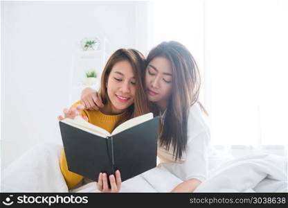 Beautiful young asian women LGBT lesbian happy couple sitting on. Beautiful young asian women LGBT lesbian happy couple sitting on bed reading book together near window in bedroom at home. LGBT lesbian couple together indoors concept. Spending nice time at home.