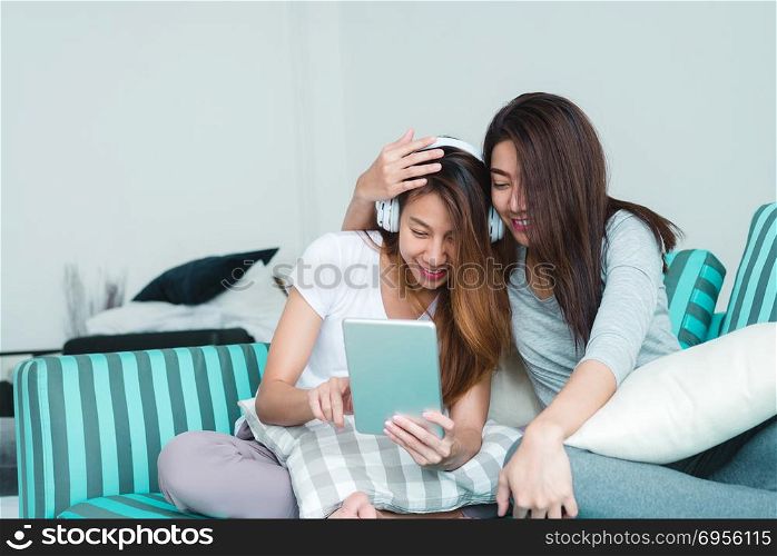 Beautiful young asian women LGBT lesbian happy couple sitting on. Beautiful young asian women LGBT lesbian happy couple sitting on sofa buying online using tablet in living room at home. LGBT lesbian couple together indoors concept. Spending nice time at home.