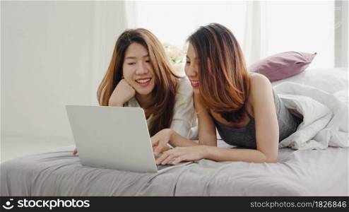 Beautiful young asian women LGBT lesbian happy couple sitting on bed hug and using laptop computer together bedroom at home. LGBT lesbian couple together indoors concept. Spending nice time at home.