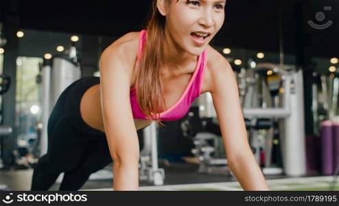Beautiful young athlete Asian lady exercise doing push-ups fat burning workout in fitness class. Sportswoman recreational activity, functional training, people working out, healthy lifestyle concept.