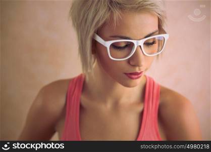 Beautiful young blond girl with short hair wearing glasses in pink style