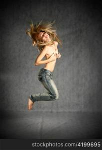 beautiful young blond woman in jeans jumping studio shot