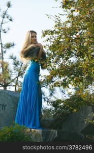 beautiful young blond woman in the park with green trees