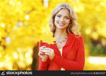 Beautiful young blond woman posing in autumn park
