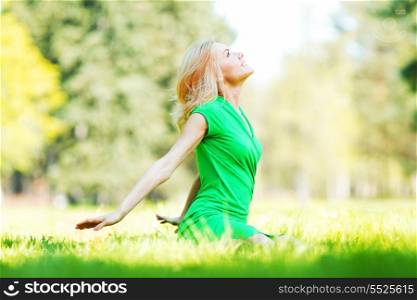 Beautiful young blond woman sitting on grass in park
