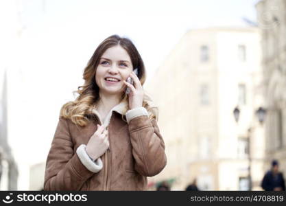 Beautiful young blonde in a fur jacket calling by phone