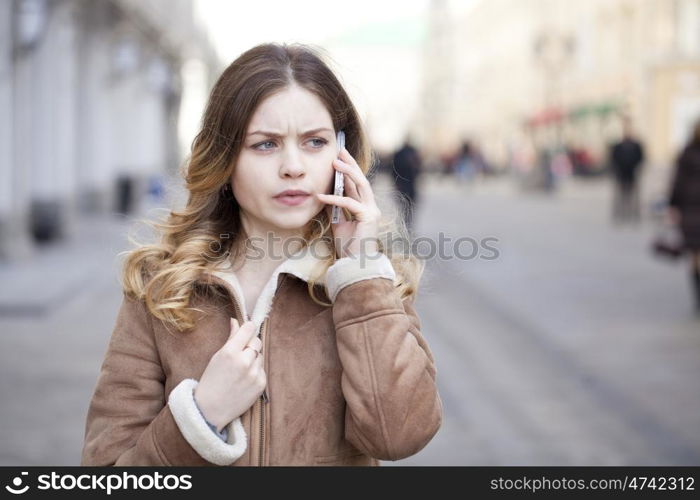Beautiful young blonde in a fur jacket calling by phone