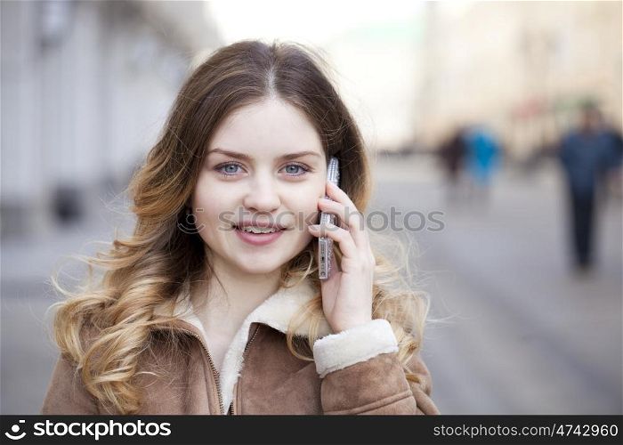 Beautiful young blonde in a fur jacket calling by phone