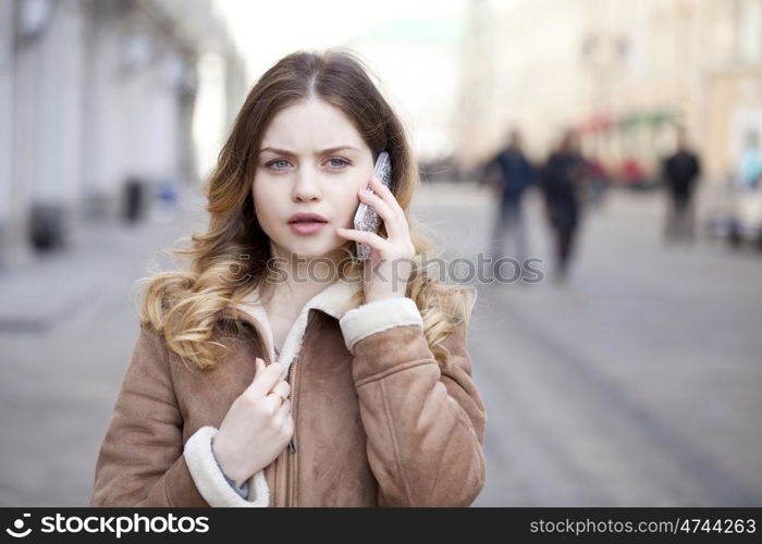 Beautiful young blonde in a fur jacket calling by phone