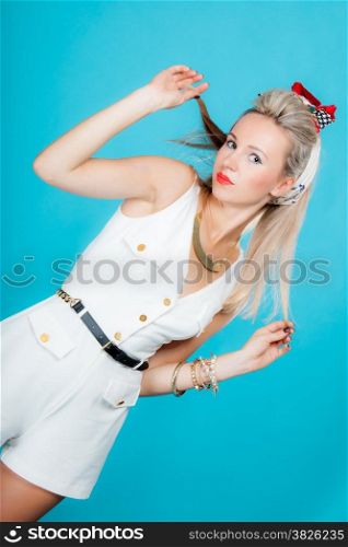 Beautiful young blonde woman in pin-up retro style vintage styling on vivid blue background