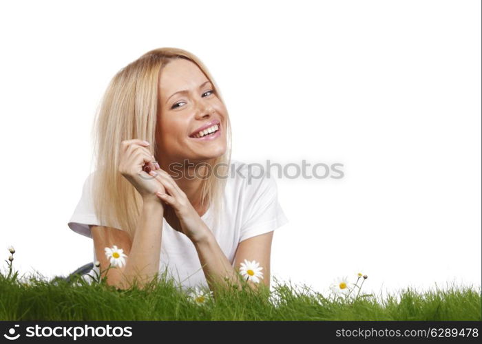 Beautiful young blonde woman lying on grass with chamomile flowers, isolated on white background