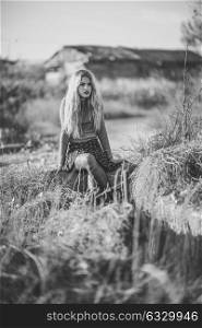 Beautiful young blonde woman, model of fashion, in rural background. Girl wearing sweater and skirt. Black and whit shoot.