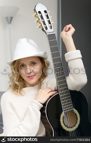 beautiful young blonde woman with hat playing the acoustic guitar