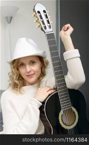 beautiful young blonde woman with hat playing the acoustic guitar