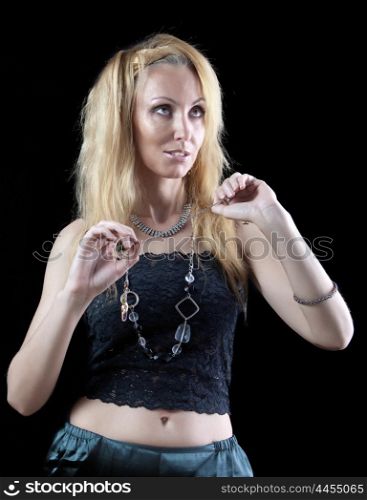 beautiful young blonde woman with long hair and jewellery on dark background.