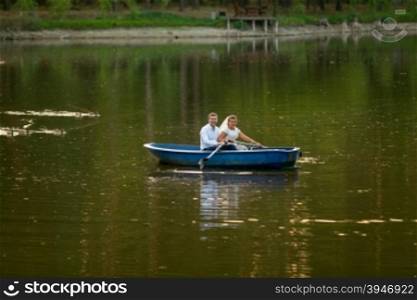 Beautiful young bride and groom riding on the boat on lake