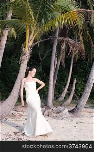 Beautiful young bride standing on the tropical wild beach