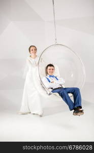 Beautiful young bride swinging groom sitting in bubble chair