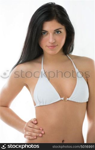 Beautiful young brunette girl wearing swimsuit. Posing against white wall background