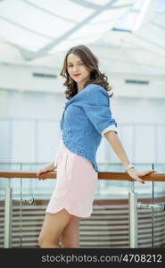 Beautiful young brunette woman in pink dress in the shop