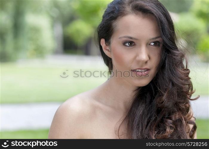 Beautiful young brunette woman looking away in park