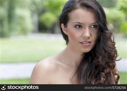 Beautiful young brunette woman looking away in park