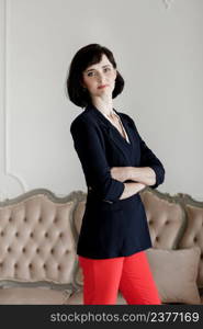 beautiful young brunette woman with folded arms. Girl with short hair in black jacket and red pants at home studio. selective focus. beautiful young brunette woman with folded arms. Girl with short hair in black jacket and red pants at home studio. selective focus.