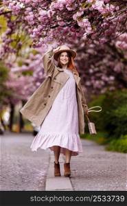 Beautiful young brunette woman with long hair flying in the wind and brown hat in a flowering garden. shallow depth of field. spring day.. Beautiful young brunette woman with long hair flying in the wind and brown hat in a flowering garden. shallow depth of field. spring day
