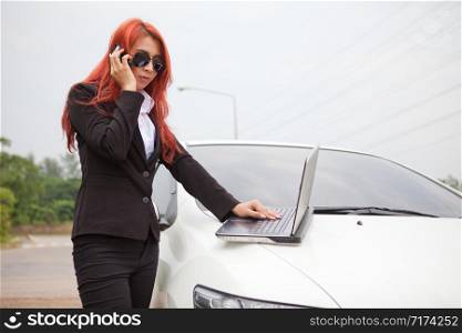 Beautiful young business asian woman using laptop and mobile phone and car