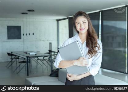 Beautiful young business Asian woman wearing casual white shirt smile with laptop in her hand in meeting room and have positive emotional,Business Startup Concept