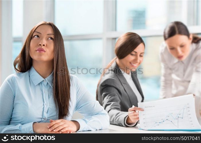 Beautiful young business executive with colleagues discussing in the background
