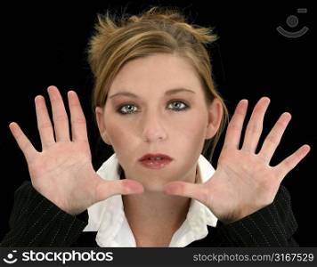 Beautiful young business woman with hands up, fingers fanned, towards camera. Shot in studio over black.