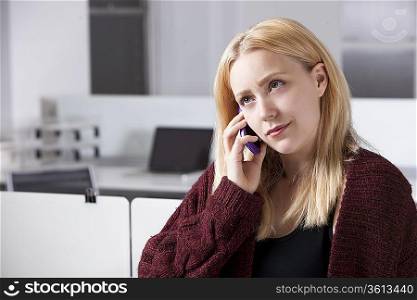 Beautiful young businesswoman using cell phone at office