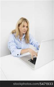 Beautiful young businesswoman using laptop at desk in office