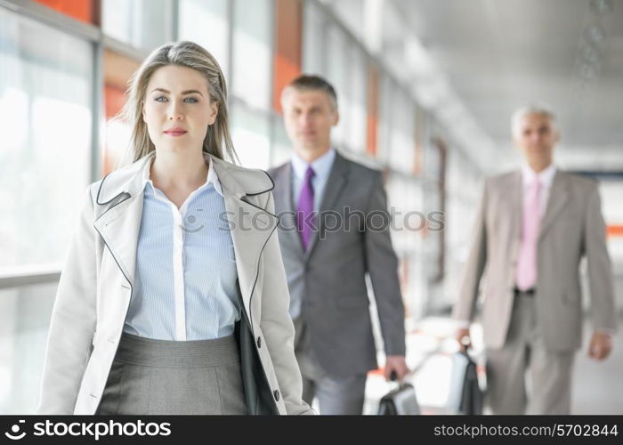 Beautiful young businesswoman walking with male colleagues in background at train platform