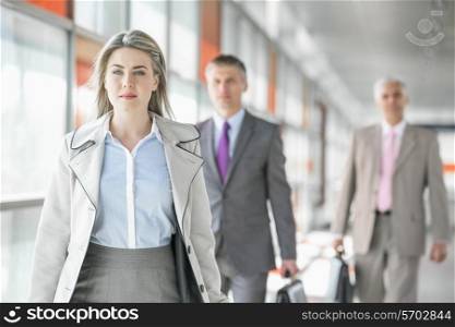 Beautiful young businesswoman walking with male colleagues in background at train platform
