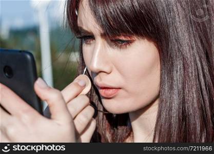 beautiful young Caucasian brown haired girl puts Foundation on her face using the phone as a mirror